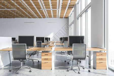 开放空间办公室的内部有白色的墙壁混凝土地板木制天花板带城市景观的大窗户和一排带椅子的白色和木制电脑桌背景图片