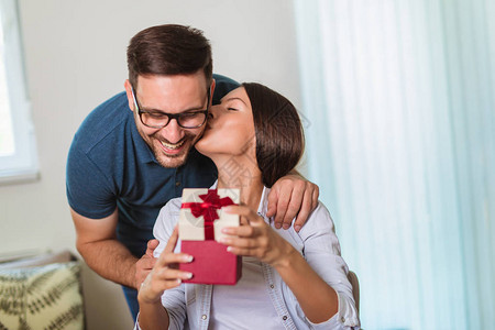 微笑的男人在家里送礼物给女朋友惊喜图片