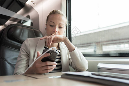 坐火车旅行时用手机交流的女商人图片
