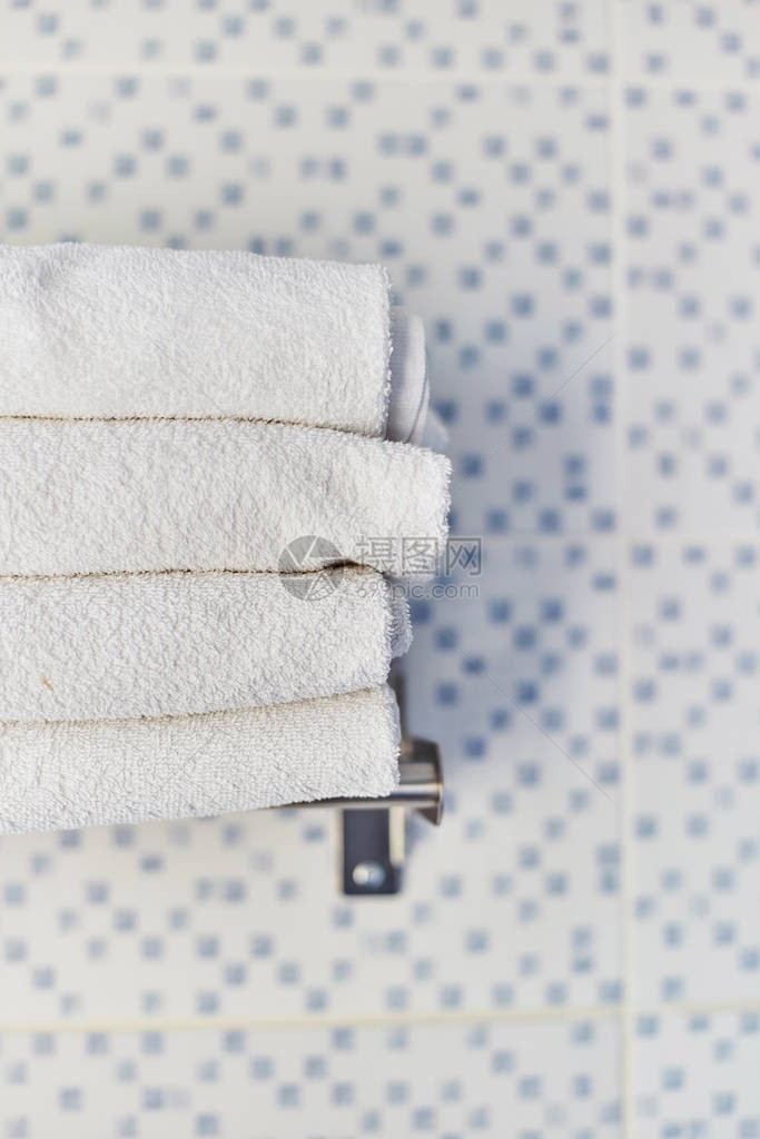 一堆白色干净的毛巾在旅馆房间里酒店洗手间的架子图片