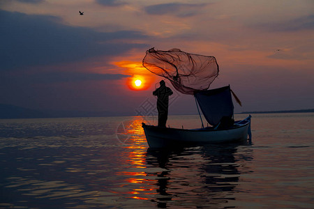 剪影渔夫在船上的渔网图片