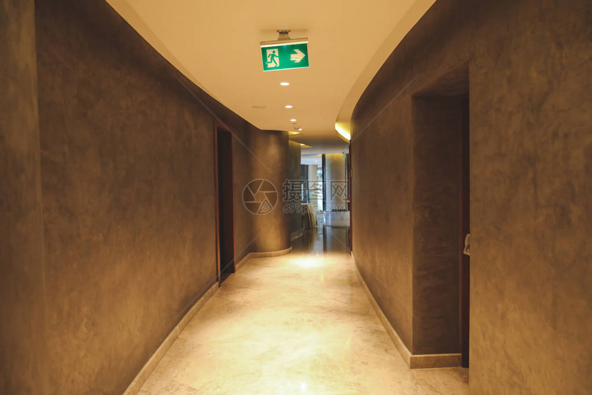 空荡的酒店或办公室走廊中的紧急出口标志或符号空荡的酒店楼层的绿色危图片