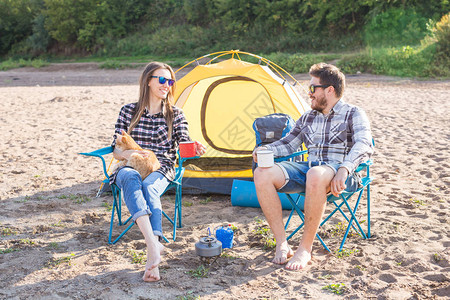 人夏季旅游和自然概念年轻夫妇在帐篷边喝茶图片