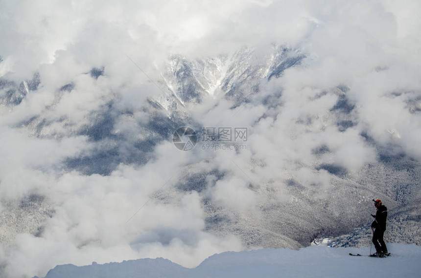 一个滑雪者站在云层的边缘图片