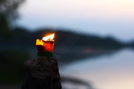 燃着热火的蜡烛在模糊黑暗的黑滨河岸反射波浪背景下闪亮地燃烧图片