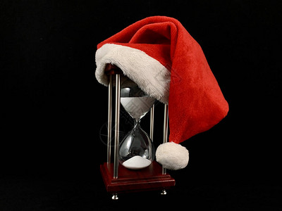 圣诞老人帽中的沙漏玻璃沙漏上的圣诞帽用于测量时间的玻璃装置图片