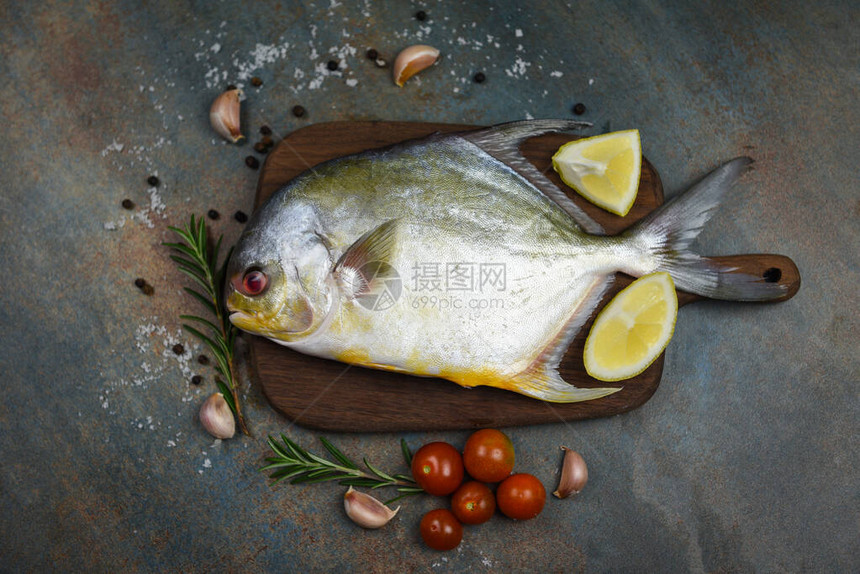 新鲜鲳鱼配香草香料迷迭香番茄和柠檬图片
