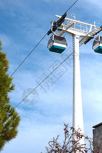 蓝色天空中的小型电动滑轮机舱在公园附近的车道上方夏季有绿树图片