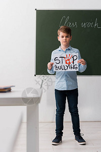 小学生在课堂上举着停止欺凌文字的标语牌图片