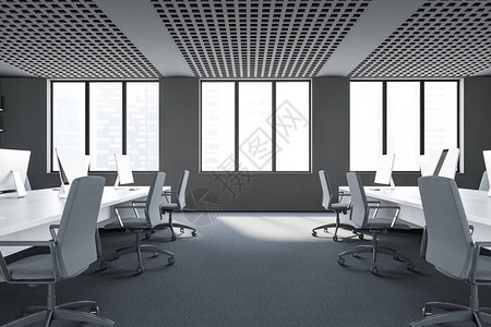 带有灰墙地毯板白计算机桌排和城市景色模糊的窗口的现代开放空间办公室侧面视背景图片