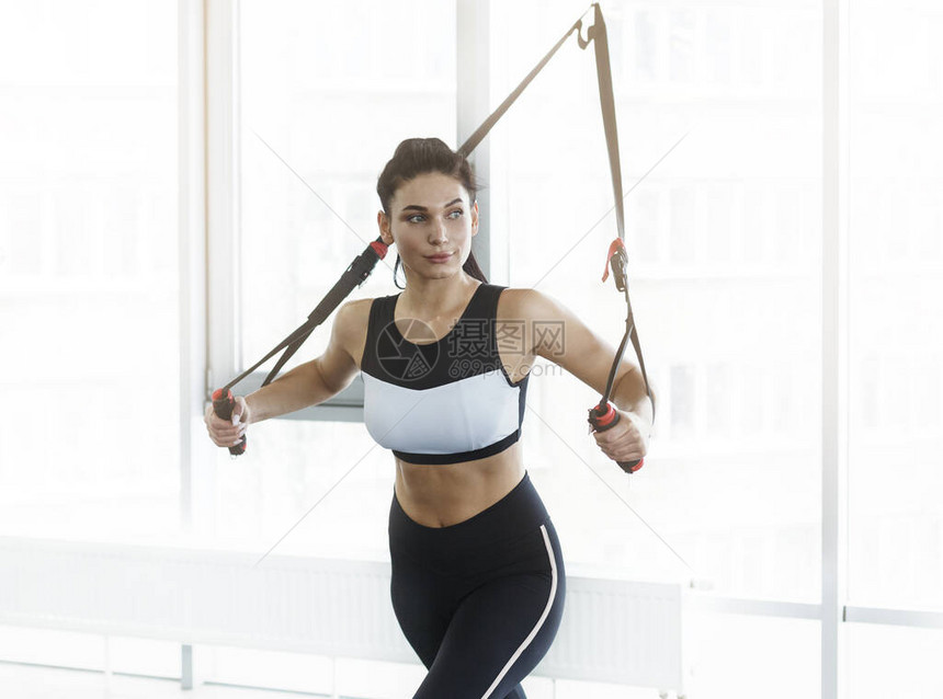 年轻女子在健身房的缆绳机上锻炼图片