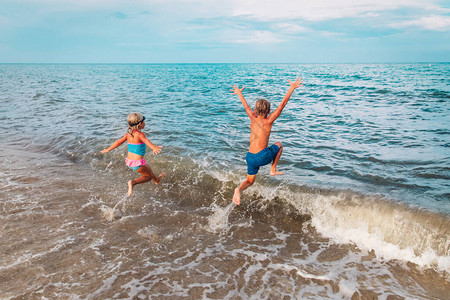 快乐的男孩和女孩在海滩上游泳图片