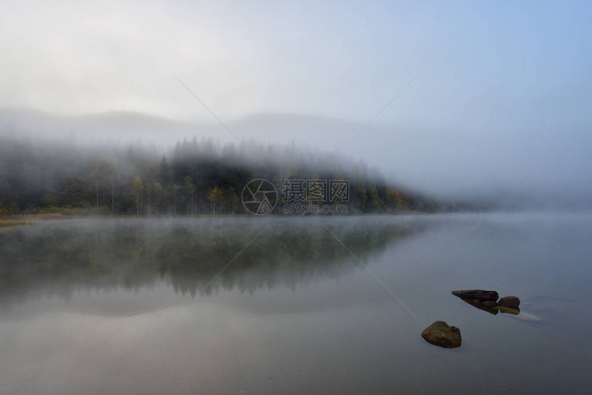 罗马尼亚StAna湖水中树林反射的山图片