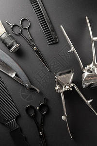 黑色的表面上是旧的美发师工具两把老式手持式理发剪梳子剃须刀美发剪刀剃须刷黑色单垂直方向背景图片