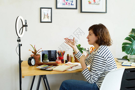 女艺术家在拍摄插画过程在家工作的创意博主使用环形照明制作大师班舒适的图片