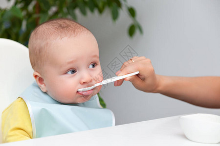 穿着彩色衣服的小男孩用勺子吃酸奶嘴巴脏兮兮的图片
