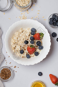 草莓蓝莓麻籽和灰色本底蜂蜜的燕麦粥高清图片