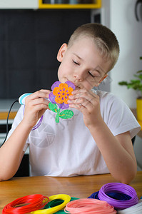 孩子用3D笔快乐男孩用彩色ABS塑料做花朵在家里的创意爱好技术休图片