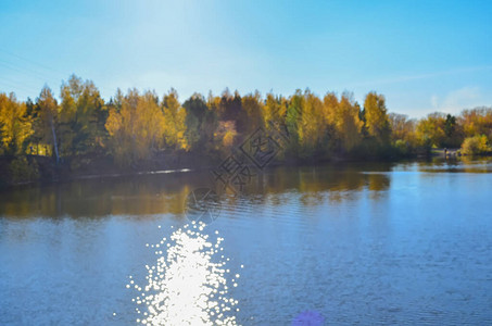 模糊的秋天风景与森林反射在湖中太阳图片