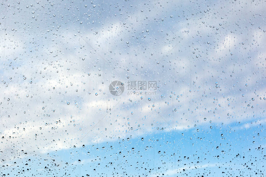 窗玻璃上的雨滴对着蓝色天空图片