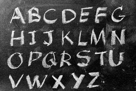 在黑板背景上用英文大写字母书写的白色粉笔手图片