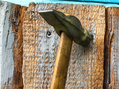 锤在带有金属末端的木柄上在木质表面上钉子金属钉子被钉进一块蓝色的木板上用锤子图片