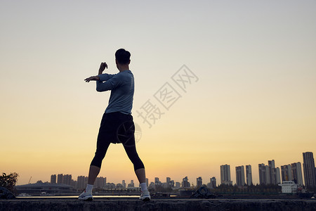 夜晚跑步年轻运动男性夕阳下运动拉伸剪影背景