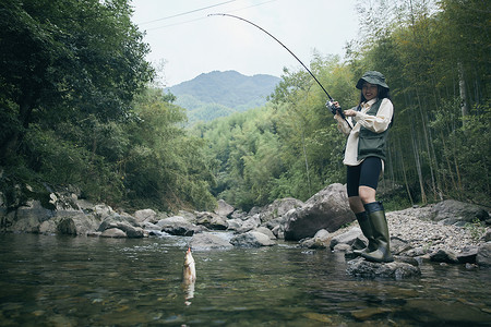 年轻女性钓鱼上钩背景图片