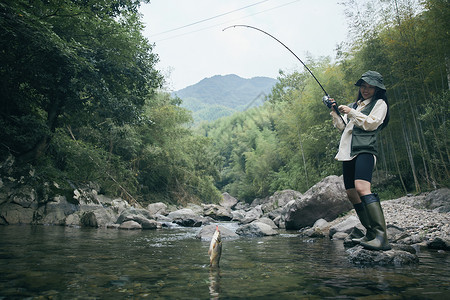青年女性户外溪流钓鱼背景图片