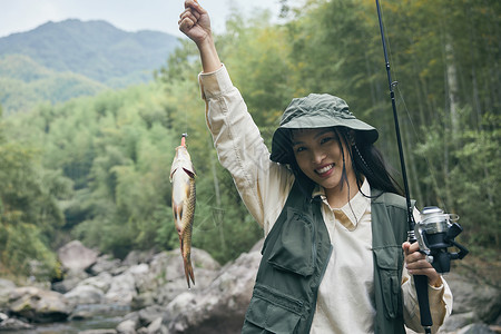 钓鱼上钩年轻女性开心手提上钩的鱼背景