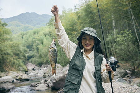 钓鱼上钩年轻女性手提上钩的鱼背景