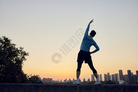 热身锻炼夕阳下男青年运动拉伸背影背景