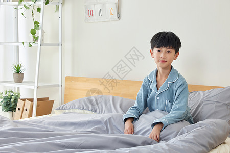 穿睡衣坐在床上的小男孩图片