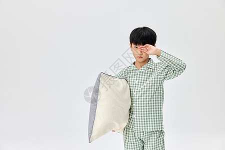 穿着睡衣抱枕头犯困的小男孩高清图片