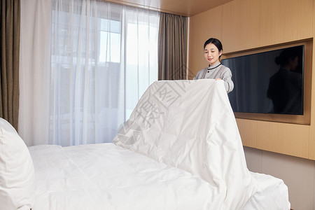 整理客房床铺的酒店女服务员背景图片