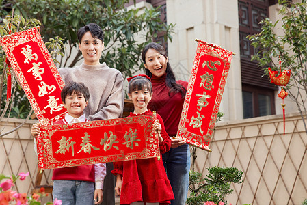 新年拜访手拿春联在院子里拜年的一家人背景