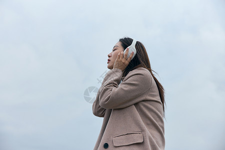 年轻女性在江边带着耳机伤感情绪图片