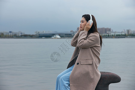 年轻女性在江边带着耳机伤感情绪背景