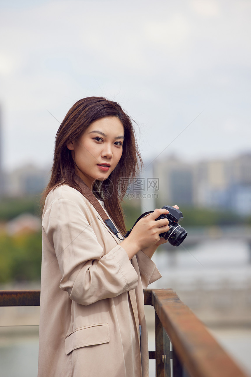 年轻女性天台手拿着相机拍照图片