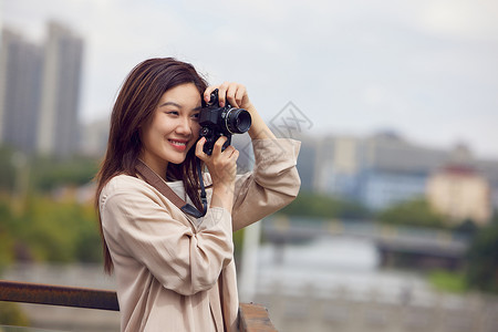 年轻女性天台拿着相机拍照背景图片