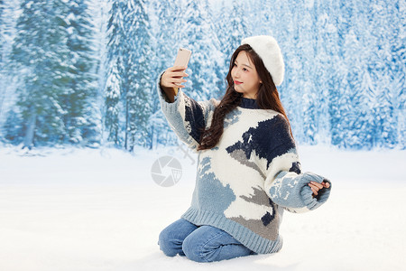 雪地里的美女使用手机自拍图片