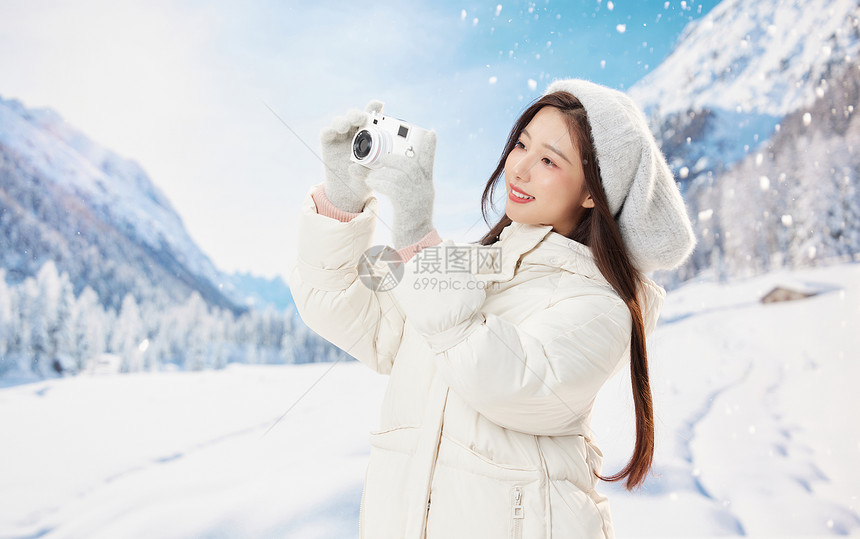 雪地里使用相机的可爱女孩图片