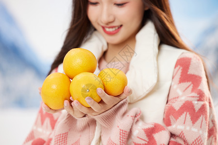 可爱的冬日女孩手捧橘子特写图片