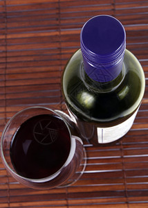 红酒瓶和木制桌上的红酒瓶和玻璃杯重图片