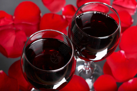 两杯带玫瑰花瓣的葡萄酒图片
