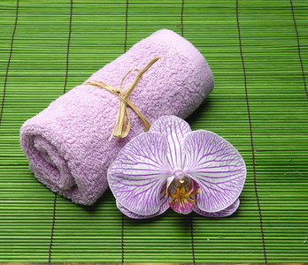绿色垫子上的粉色兰花和粉色毛巾图片