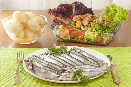 盘子里的鳕鱼毛鳞鱼配沙拉和煮熟的新土豆图片
