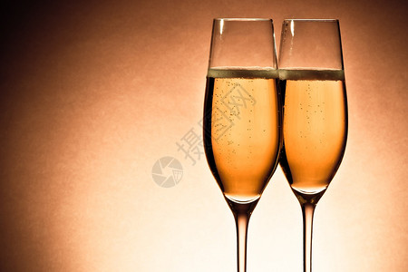 两杯香槟配有黄金泡和棕色背景文字空图片