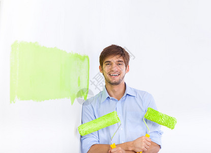 快乐的年轻人用绿色白墙漆他的新公寓图片