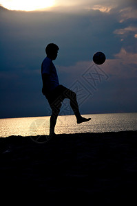 沙滩上踢足球的人剪影背景图片